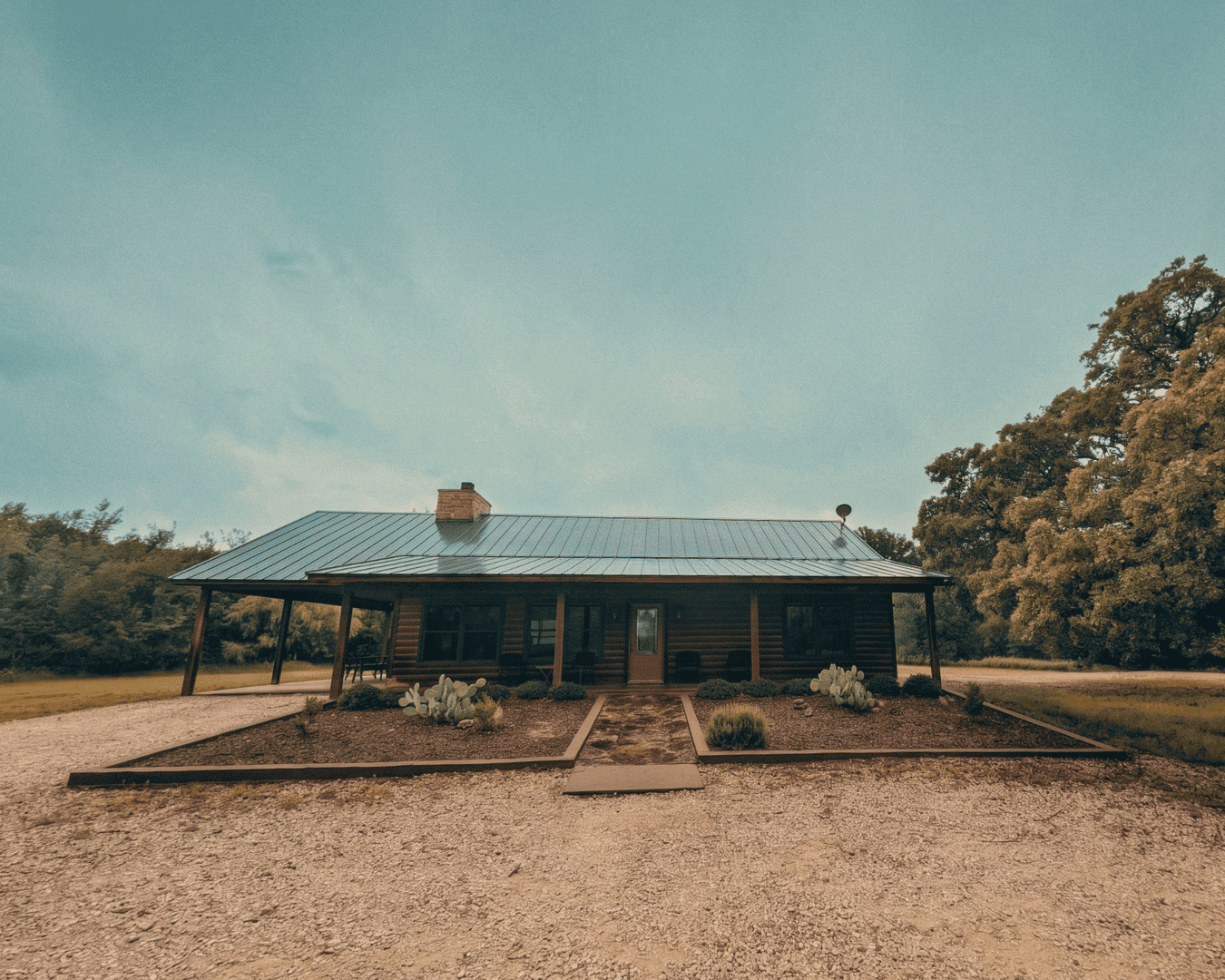 Rustic ranch house with metal roof and surrounding landscape.