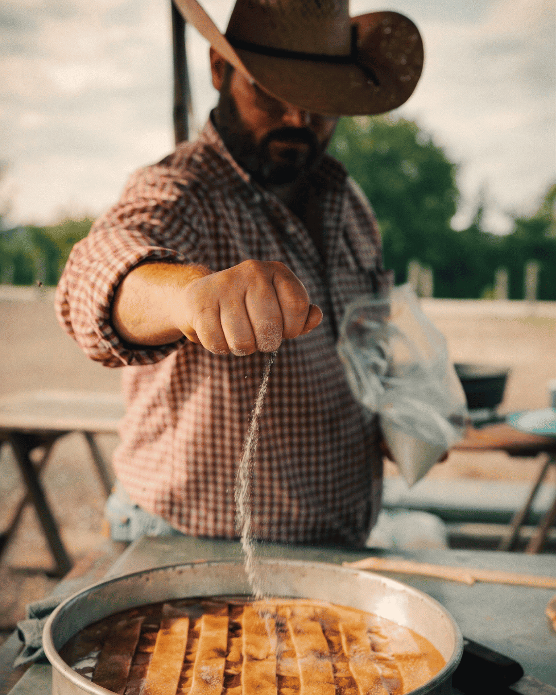 Farmer sprinkling salt on food at outdoor market.