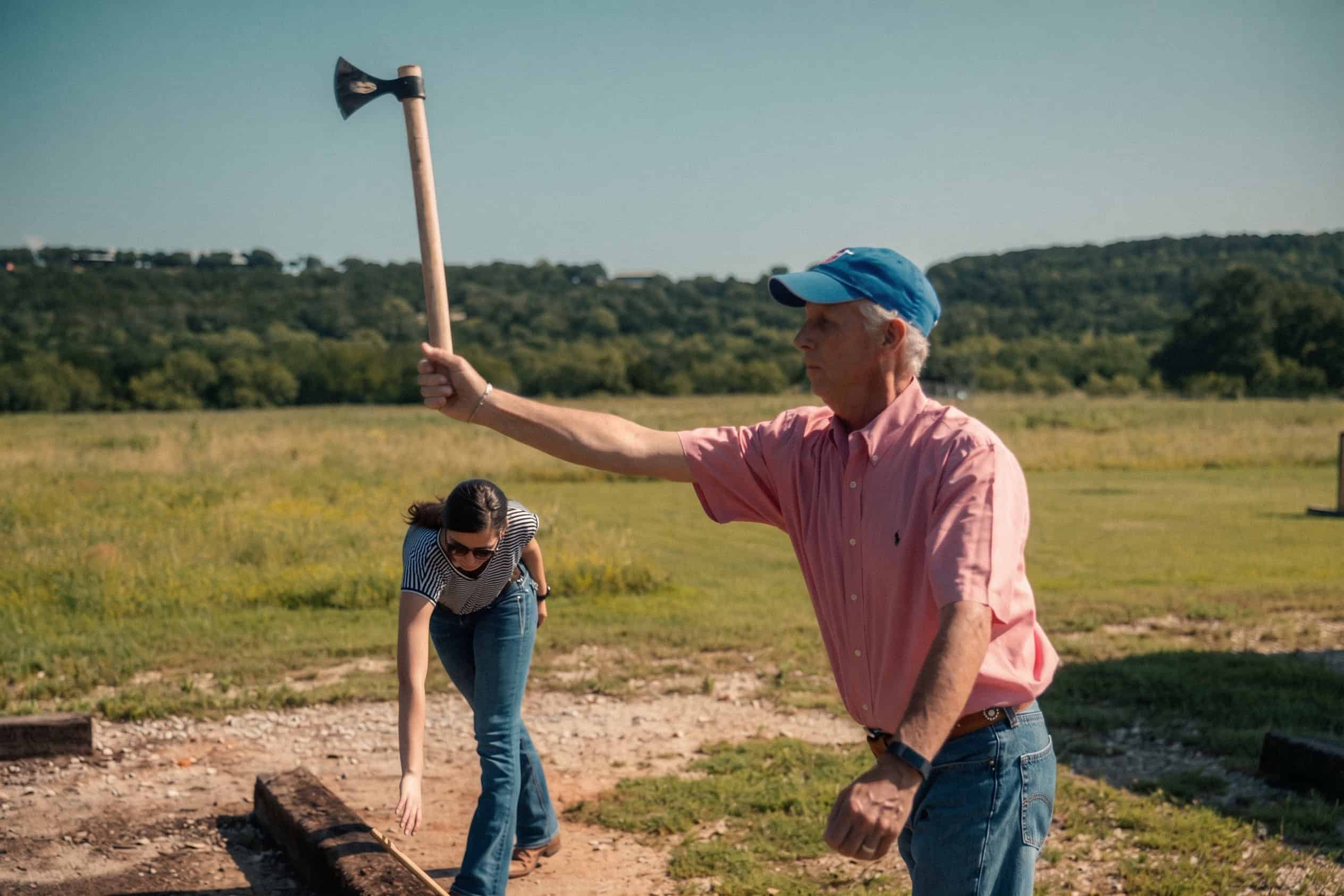 Man swinging an axe outdoors at Wildcatter Ranch.