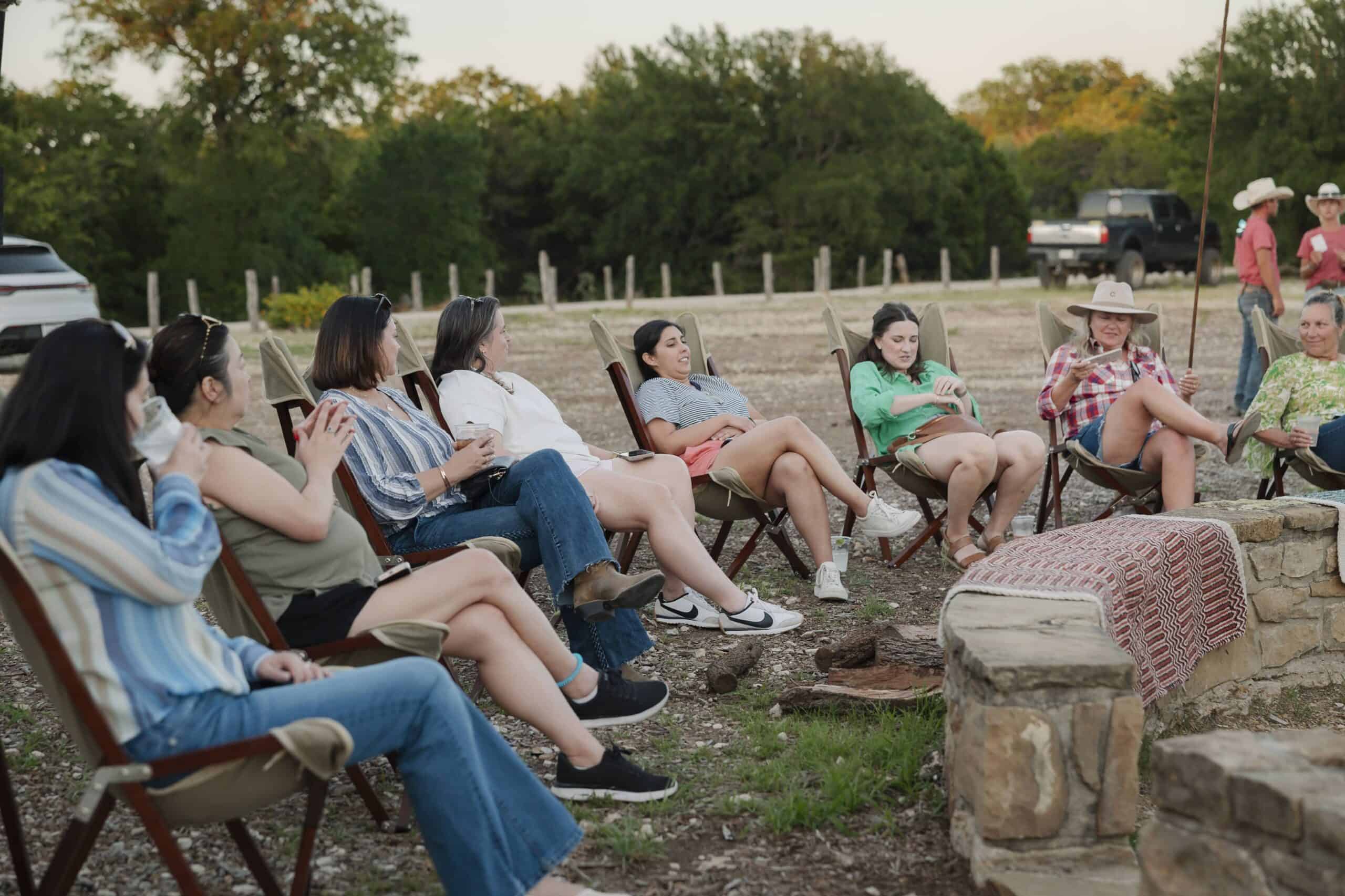 Group of people sitting around a campfire at Wildcatter Ranch.