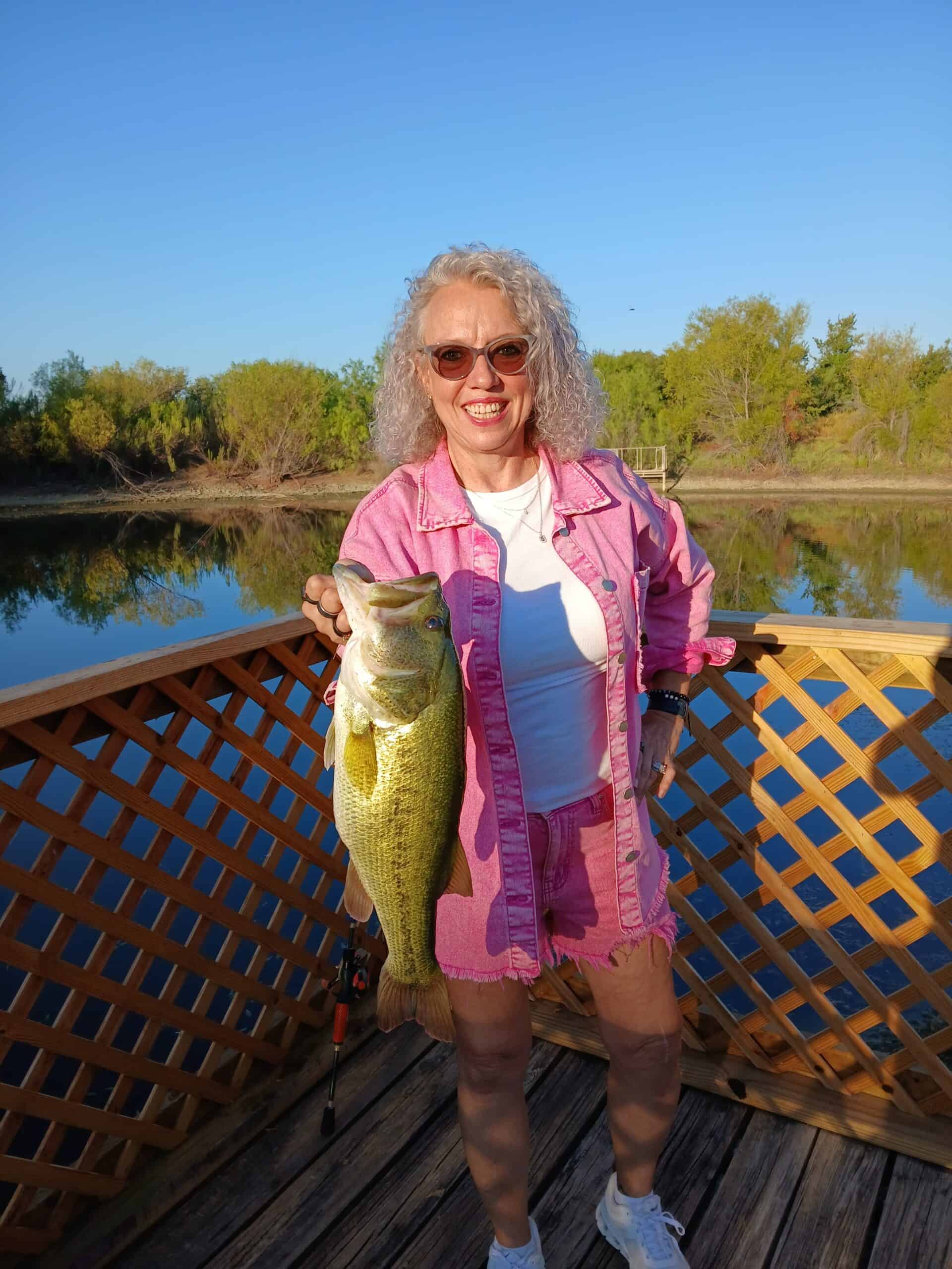 Woman holding a large fish at Wildcatter Ranch outdoor fishing dock.
