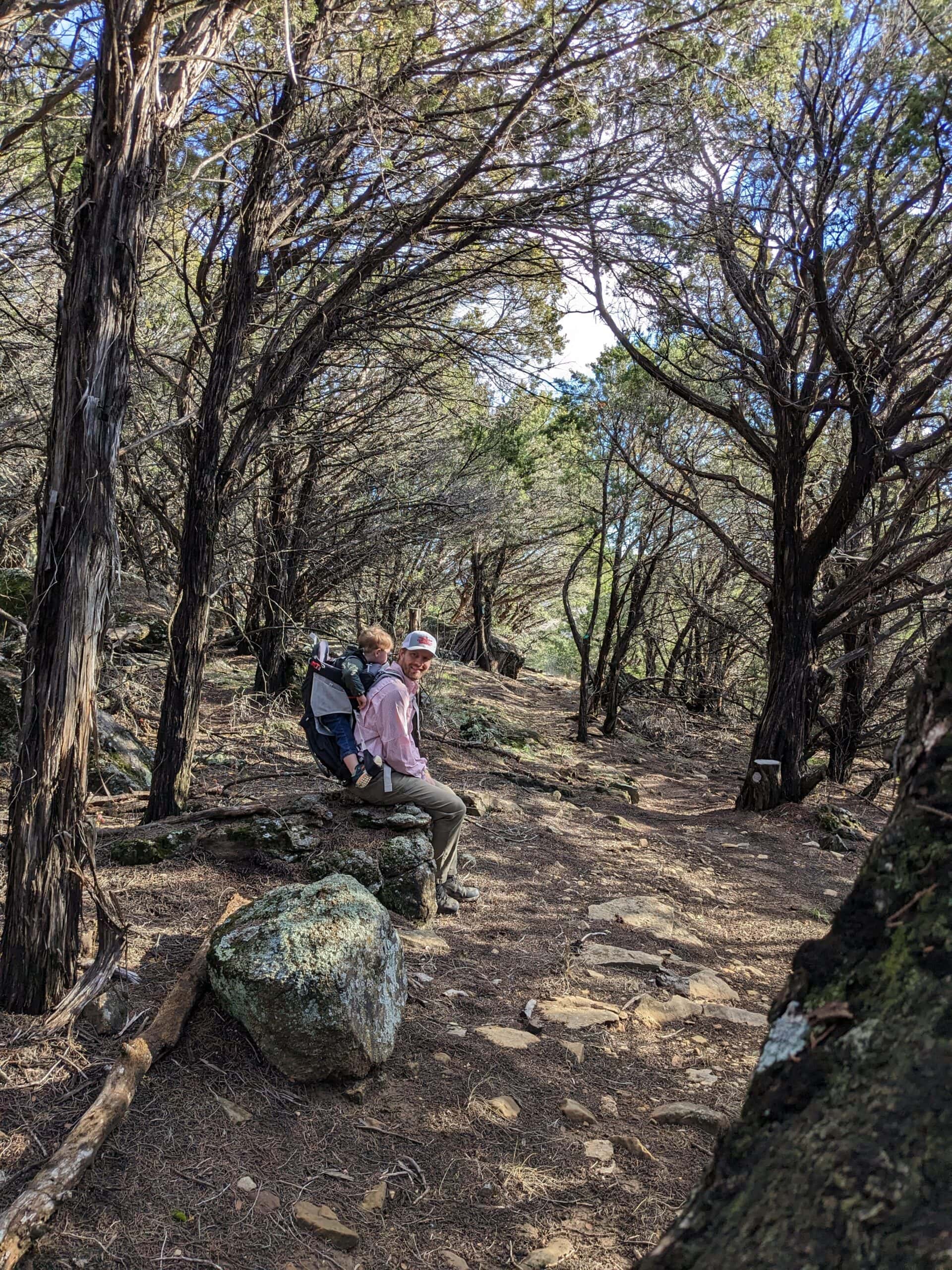 Hikers resting on a trail surrounded by trees at Wildcatter Ranch.